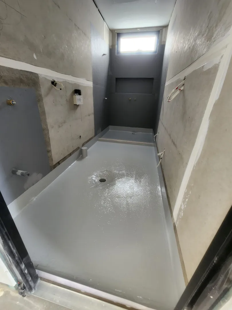 Empty shower under construction with plumbing visible.