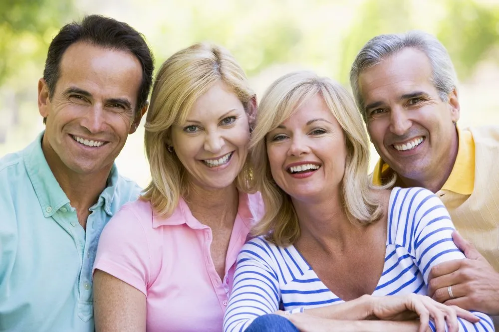 Group of four smiling friends outdoors.